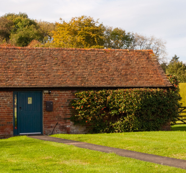 A farmhouse building with blue door that hosts Hotbox Studios in Hook, South West England.